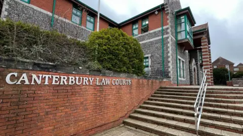 BBC Steps leading up to a large stone and brick building. The words Canterbury Law Courts are written along the wall beside the steps.