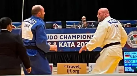 Judo Veterans World Champion Action shot of a fight between two men. One is wearing a white judo uniform and the other is wearing blue