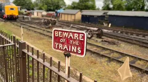 Emma Baugh/BBC Beware the trains sign beside railway track