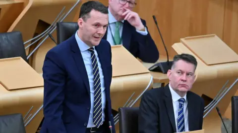 Getty Images Russell Findlay speaks at Holyrood while Murdo Fraser watches on.