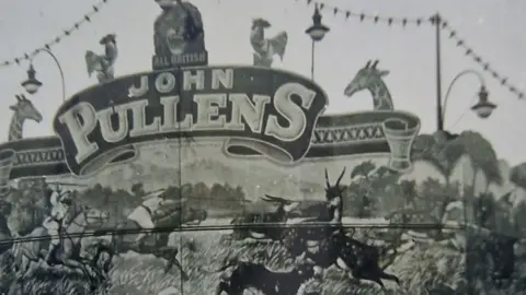 Jon Pullin A black and white image of a fairground amusement banner with John Pullens written on it 