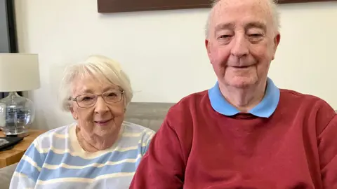 Meurig and Sheila Price, sitting down, smiling at the camera