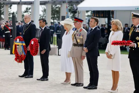 LUDOVIC MARIN/AFP Britain's King Charles III (C), Britain's Queen Camilla (3rdL), France's President Emmanuel Macron (3rdR), French President's wife Brigitte Macron (2ndR) and Britain's Prime Minister Rishi Sunak (2ndL) attend the UK Ministry of Defence and the Royal British Legion's commemorative ceremony, 6 June 2024