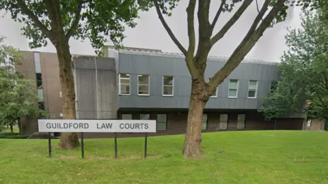 Google A Google Street image of a grey building with a sign in the foreground which says "Guildford Law Courts".