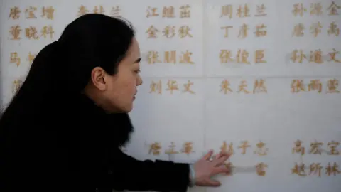 Getty Images The wife of an organ donor touches her husband's name on a memorial for Chinese organ donors