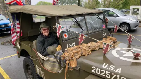 BBC A woman in a World War Two Jeep decorated with bunting.