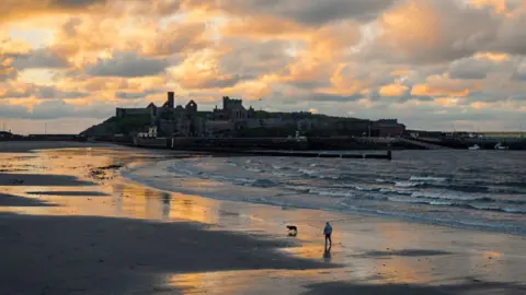 MANXSCENES Man walking dog on Peel Beach