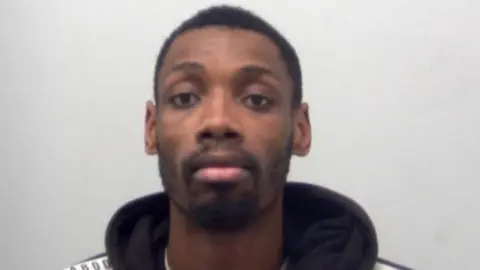 Essex Police Custody mugshot of Kiernan Hughes-Mason, who is wearing a black hoodie and expressionless while looking at the camera.