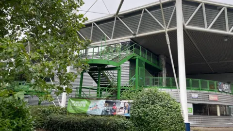 BBC The exterior of the Link Centre in Swindon. Image shows green staircase and advertising sign.