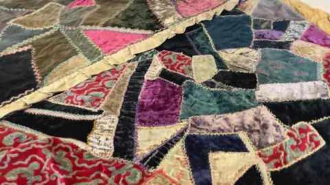 A close-up view of a colorful patchwork quilt showing velvet fabric pieces.