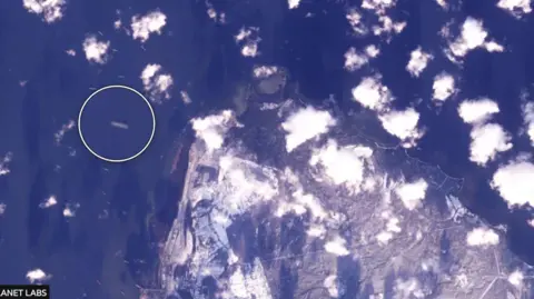 Planet Labs Satellite image of a coastline surrounded by ships.