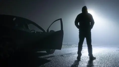 Getty Images Shadowy man outside car