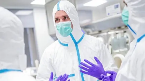 Science Photo Library Medical staff in protective suit