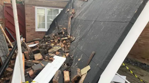 A roof on its side surrounded by rubble with some pieces of roof. 