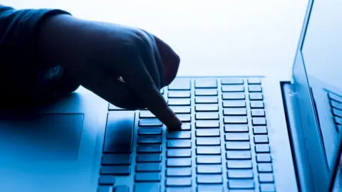 PA Media Person pressing a button on a laptop computer