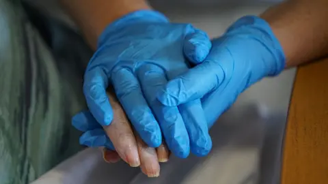 Getty Images holding hands in plastic gloves