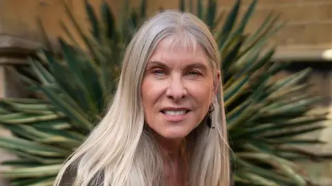 Getty Images Sharron Davies has long, blonde hair. She is smiling at the camera 