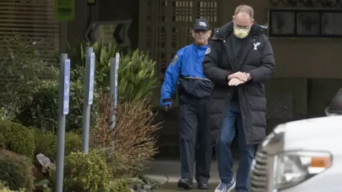 Karen Ducey Two men emerge from a nursing home, one in official uniform and the other washing his hands, that reported several cases of coronavirus in Washington State.