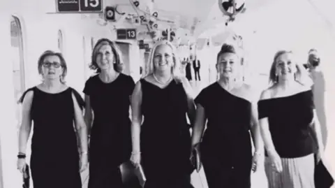 Five sisters Julie Madden, Christine Rushton, Carol Kenny, Maria Hewitt and Irene Ashworth all wearing black evening dresses and holding clutch handbags aboard Cunard's Queen Victoria cruise ship in 2018.