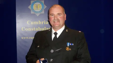 Cumbria Constabulary PC William "Bill" Barker pictured in formal police uniform picking up an award