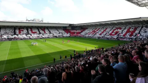 PA Media A huge demonstration by Bristol City fans ahead of the Leeds United match at Ashton Gate. Thousands of fans hold white and red squares aloft "FLY" And "HIGH" After the death of manager Liam Manning, in different stands in memory of his son.