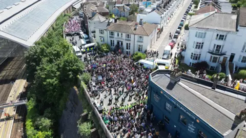 Eddie Mitchell An aerial view of thousands of people crowding a busy street. 