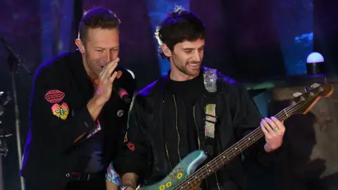 Getty Images Chris Martin and Guy Berryman of Coldplay on stage in London in October 2021