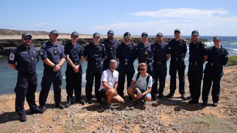 Royal Navy a group of about a dozen Royal Navy sailors posing for a photo