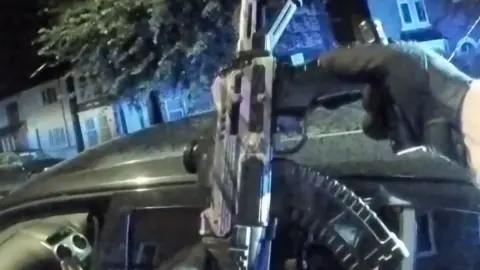 Police officer holding a toy gun. It looks realistic.