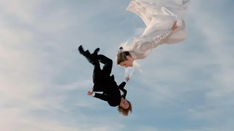Getty Images A skydiving couple, with man in a morning suit and the woman wearing a wedding dress