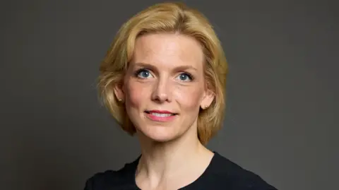 UK Parliament Parliamentary Portrait of Samantha Niblett. She has a blonde bob haircut and is wearing a black dress.