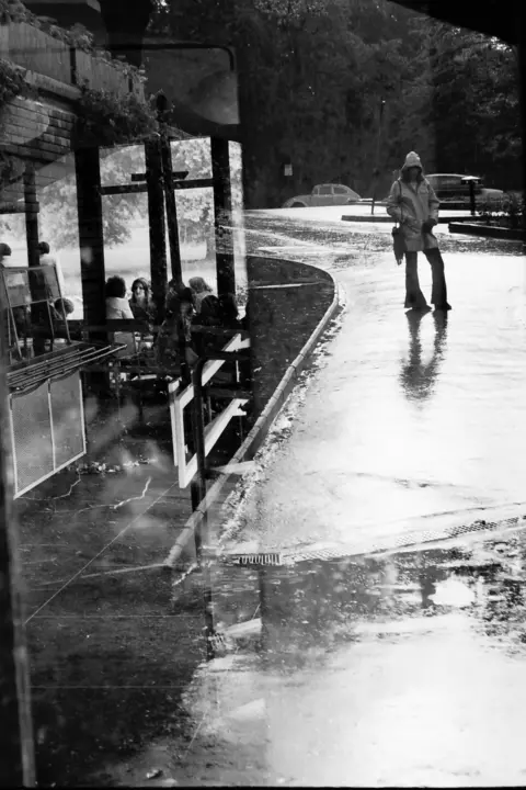 Denkan Gray is a wet scene outside a café in 1970