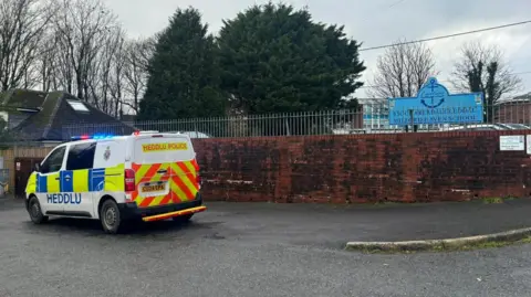 Pembrokeshire Herald A police van and car are outside the entrance to the school. A sign with the school name can also be seen.