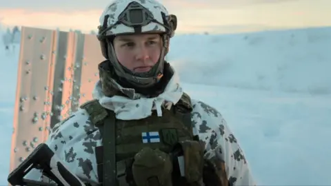Soldier stands in winter military kit with helmet and body armour in the snow