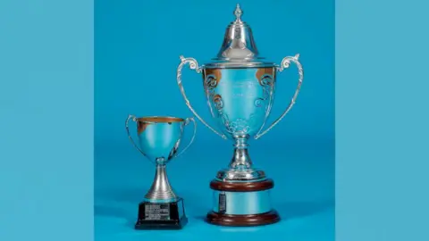 Stephen Tierney A small trophy beside a large silver trophy.