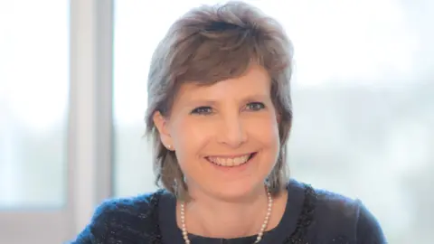 Homecare Association A head and shoulders shot of Dr Jane Townson smiling at the camera. She has short light brown hair and is wearing a navy top and a pearl necklace. 