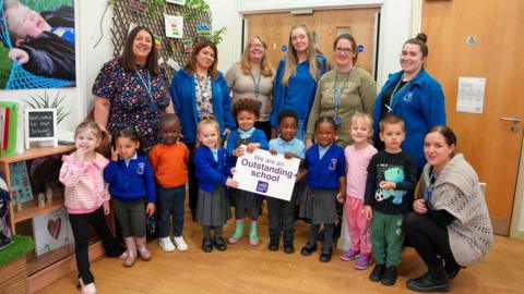 Children are celebrating Low Hill Nursery's Outstanding Ofsted judgment. They are pictured with, left to right, Natalie Showell, Headteacher, Runak Hamad, UQT, Emma Harris, SENCO, Hayley Tipple, Early Years Practitioner, Tara Smith, Pastoral Support, Toni Jones, Early Years Practitioner, and Samantha Phillips, Pastoral Support.