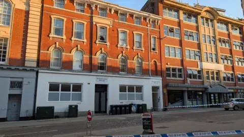Jacob Ottaway/BBC a block of flats with several of the windows damaged 