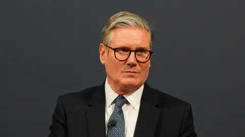 Carl Court/PA Wire A head and shoulders shot of Sir Keir Starmer wearing a black suit jacket over a white shirt and tie. He is looking slightly off to his left.