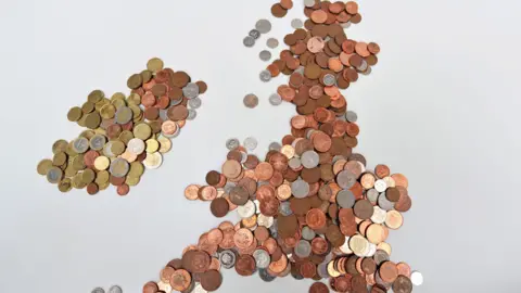 A map of the UK made up of coins. There are 1p, 2p, 10p pieces, as well as euros.