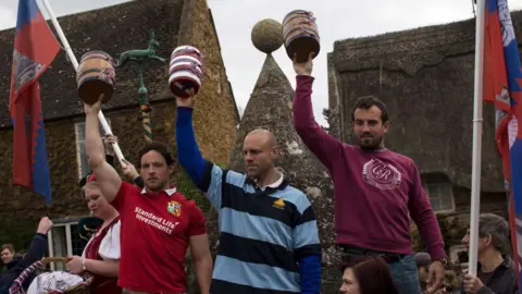 Getty Images Three men holding barrels aloft into the air 