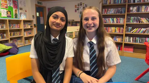 Two girls in school uniform - a white shirt with a black and blue tie