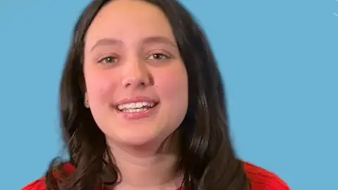 A close up shot of a young woman in front of a blue background