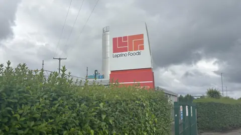 A sign saying Leprino Foods. It is a white sign with the words in black. The logo red and orange logo sits above it