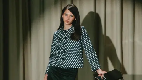 Brit Awards Sienna Spiro wears a black and white patterned jacket with black buttons. She has dark brown hair. 