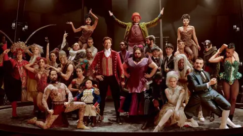 20TH Century Fox A picture from The Greatest Showman film. The picture shows a large group of the cast in a circus ring with PT Barnum, portrayed by Hugh Jackman, in the centre.