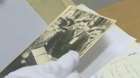 Archivist handles photo of John Traynor on a later pilgrimage with special white gloves