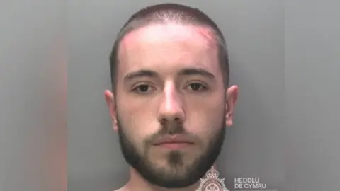 South Wales Police Kane Evans in custody photo with shaved head and facial hair