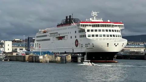The Manxman ferry moored in Douglas Bay. It is a large white vessel with red and black markings and the Isle of Man Steam Packet Company logo on the side.