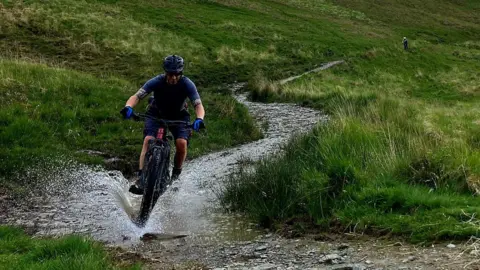 Jamie Cox Jamie Cox on a training ride through rough terrain